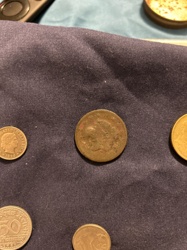 Due to the heavy wear, the exact coin name for the central coin is difficult to determine without clearer images of both sides. It might be a British Penny or Halfpenny, or a coin from another European country, given the other coins in the image. The coin on the left is a Swiss 10 Rappen.